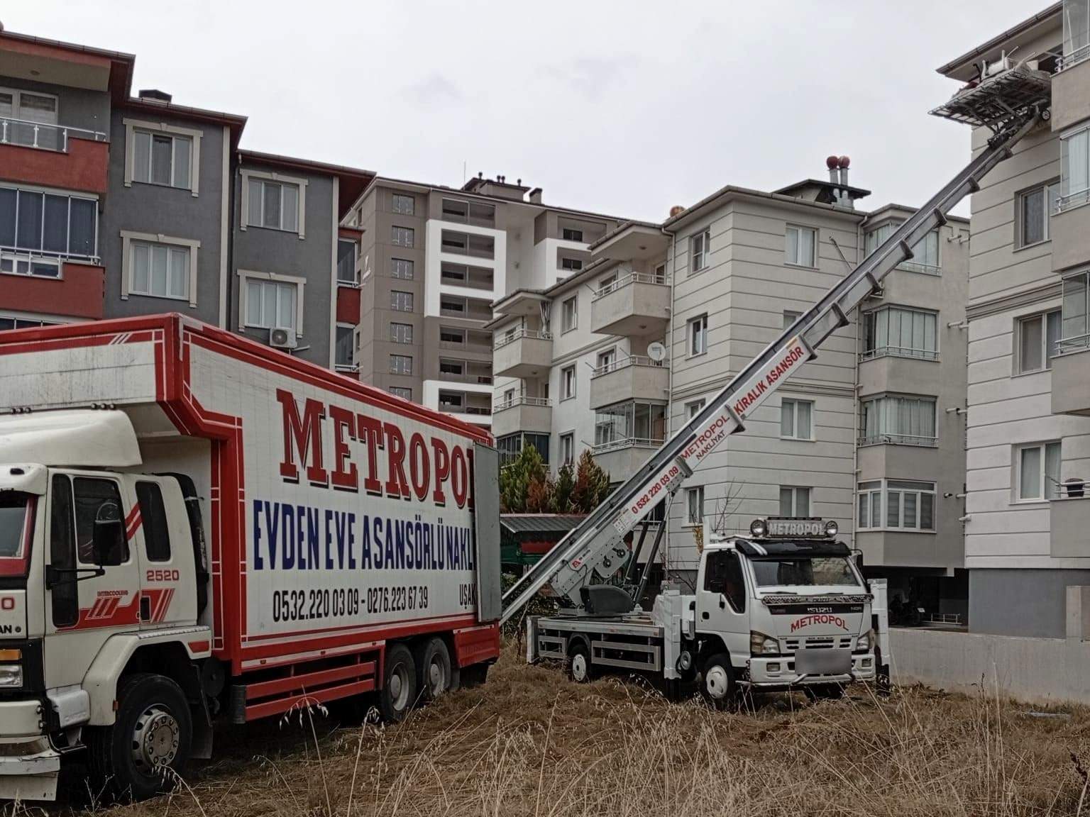 Uşak’ta bir apartmanın üst katına uzanan Metropol kiralık asansörü ve önünde asansörlü nakliyat kamyonu