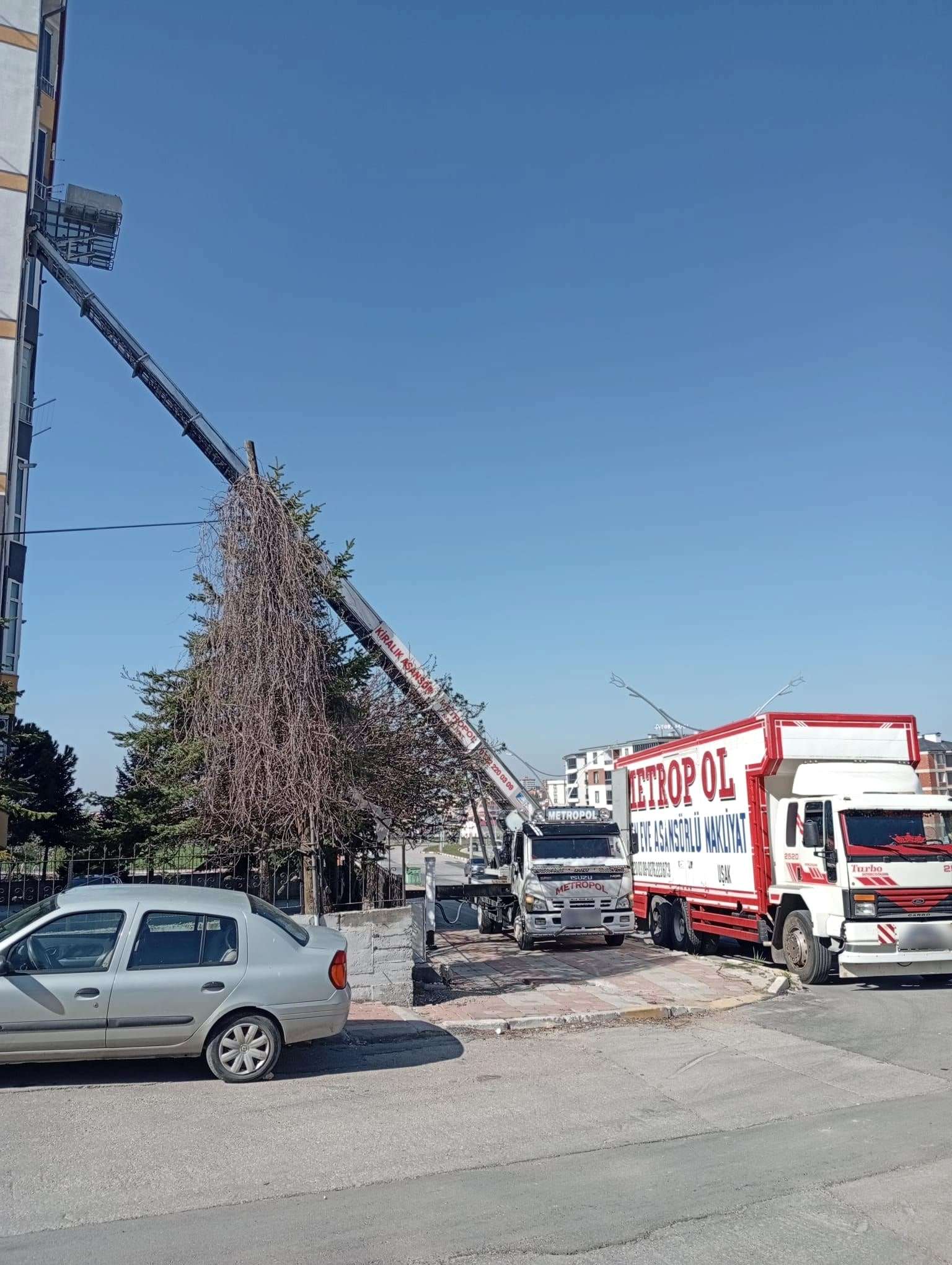 Köşe başında bir binanın üst katına çapraz açılmış asansör, önünde iki Metropol aracı