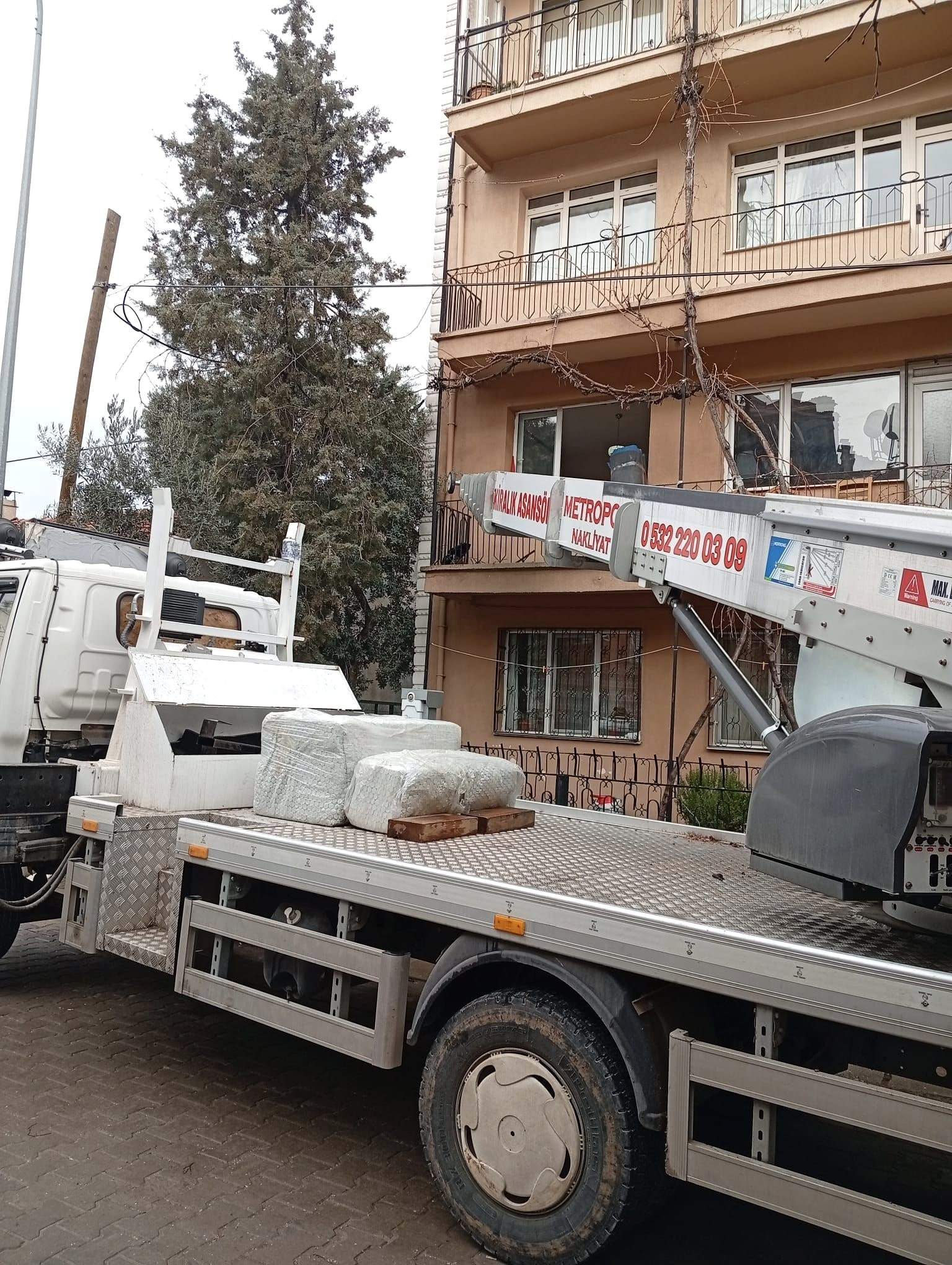 Asansör takılı Metropol aracının kasasında streçlenmiş eşyalar; kiralık asansör balkon hizasına uzanıyor